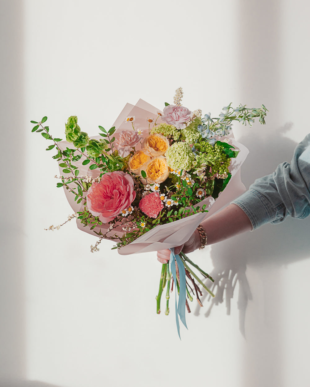 Bouquet of flowers held by a person against a white background