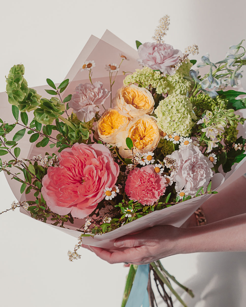 Bouquet of flowers held by a person with a light background