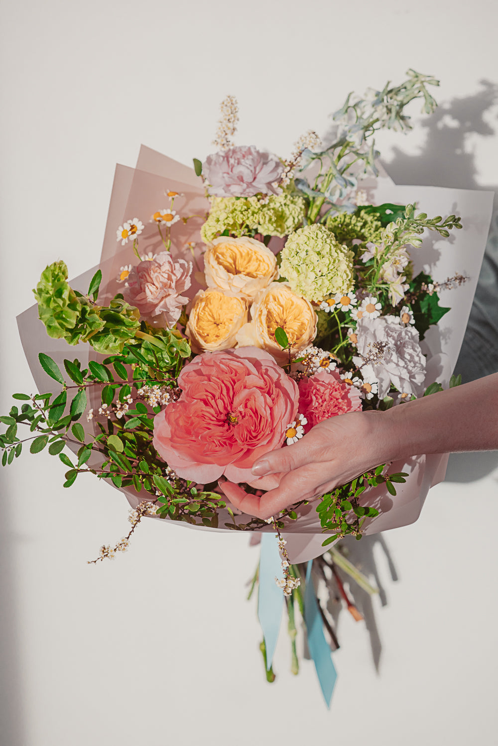 Bouquet of flowers held by a hand on a light background